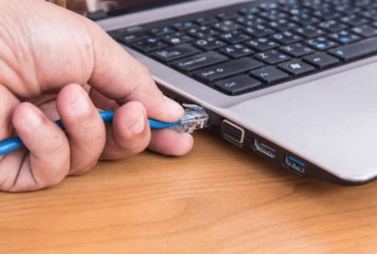 someone plugging an Ethernet cable into a laptop RJ45 port